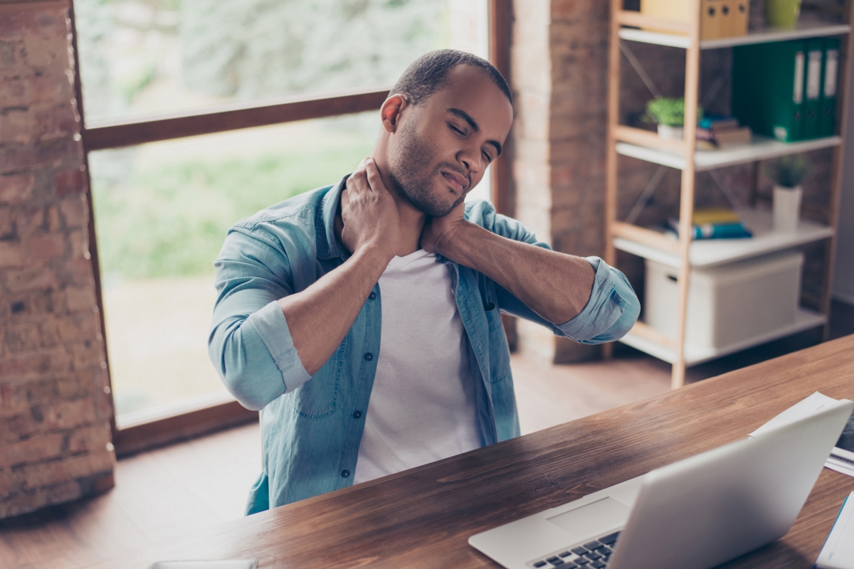 young man working at laptop experiencing neck pain