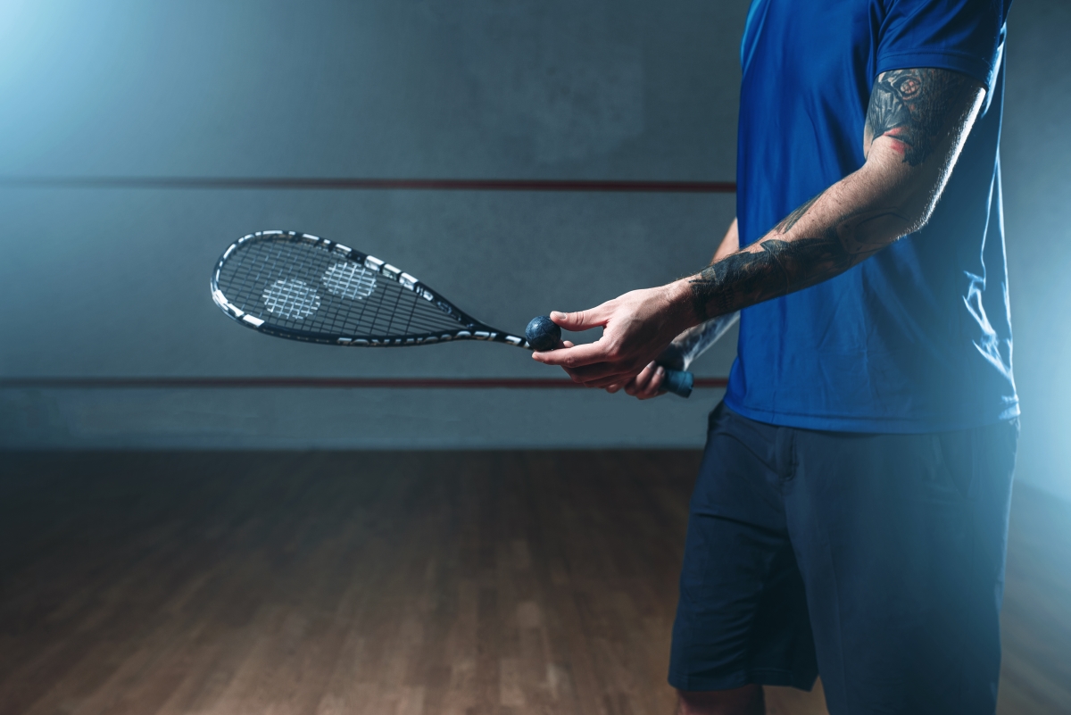 Male squash player training on indoor court