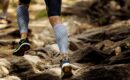 marathon runner running rocks in mountain. closeup of legs compression socks and shoes