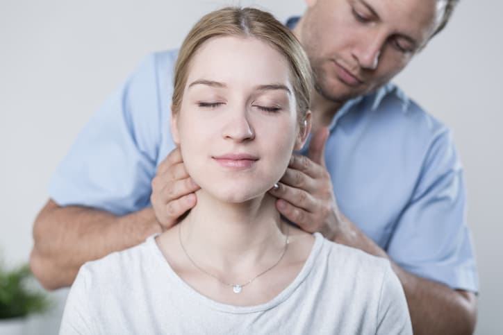 Chiropractor or therapist performing a neck treatment on a young woman