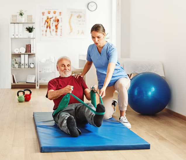 Physical therapist assisting a senior man with resistance band exercises