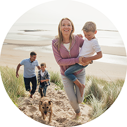 a-family-and-their-dog-walking-up-a-sandy-hill-at-the-beach