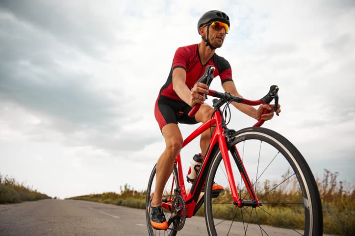 Road cyclist riding a red racing bike on an open road
