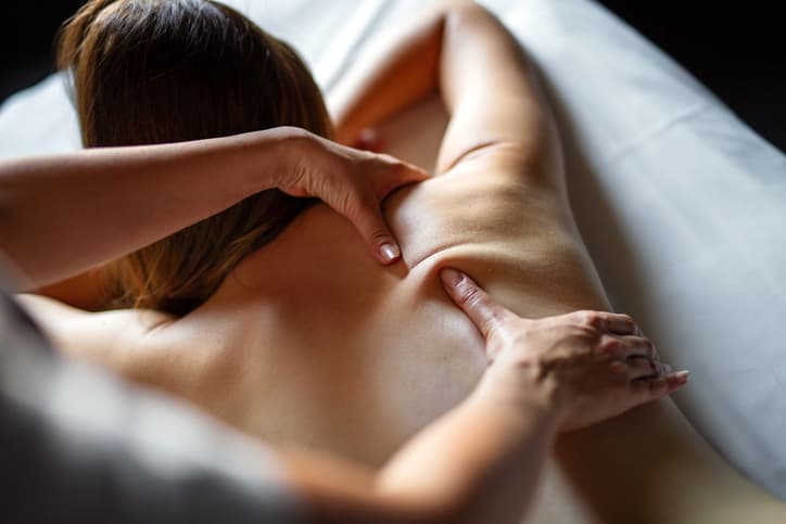 Woman receiving a therapeutic shoulder and back massage at a spa
