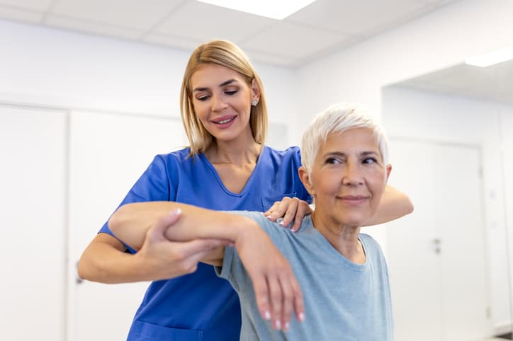 Physical therapist helping a senior woman with shoulder rehabilitation exercises
