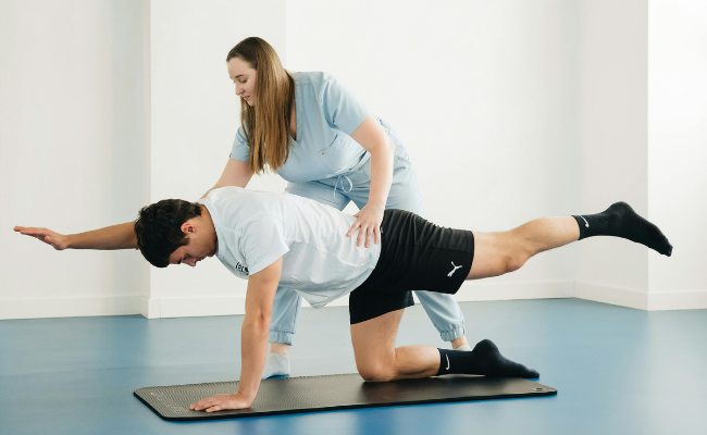 A patient practices core and balance control with therapist support during mobile physiotherapy in Surrey
