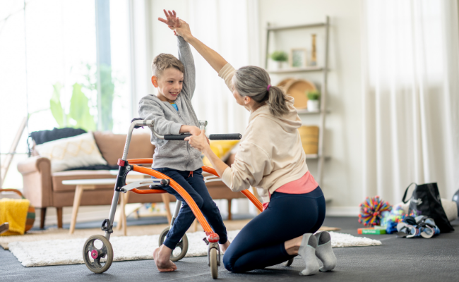 Pediatric physiotherapist helping a child practice walking at home in Calgary