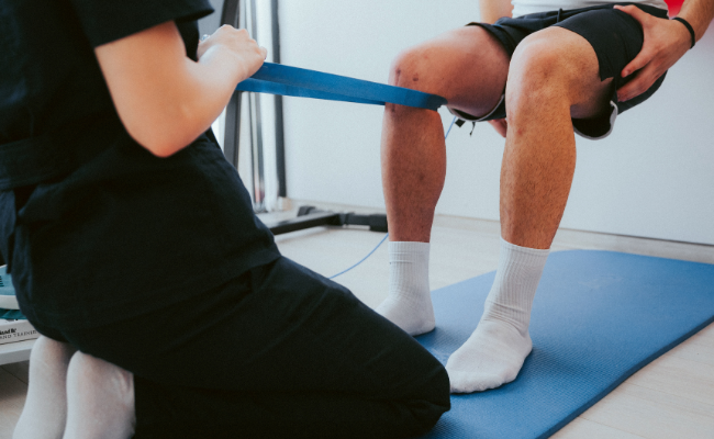 A patient performs seated knee strengthening with a resistance band after surgery in Edmonton