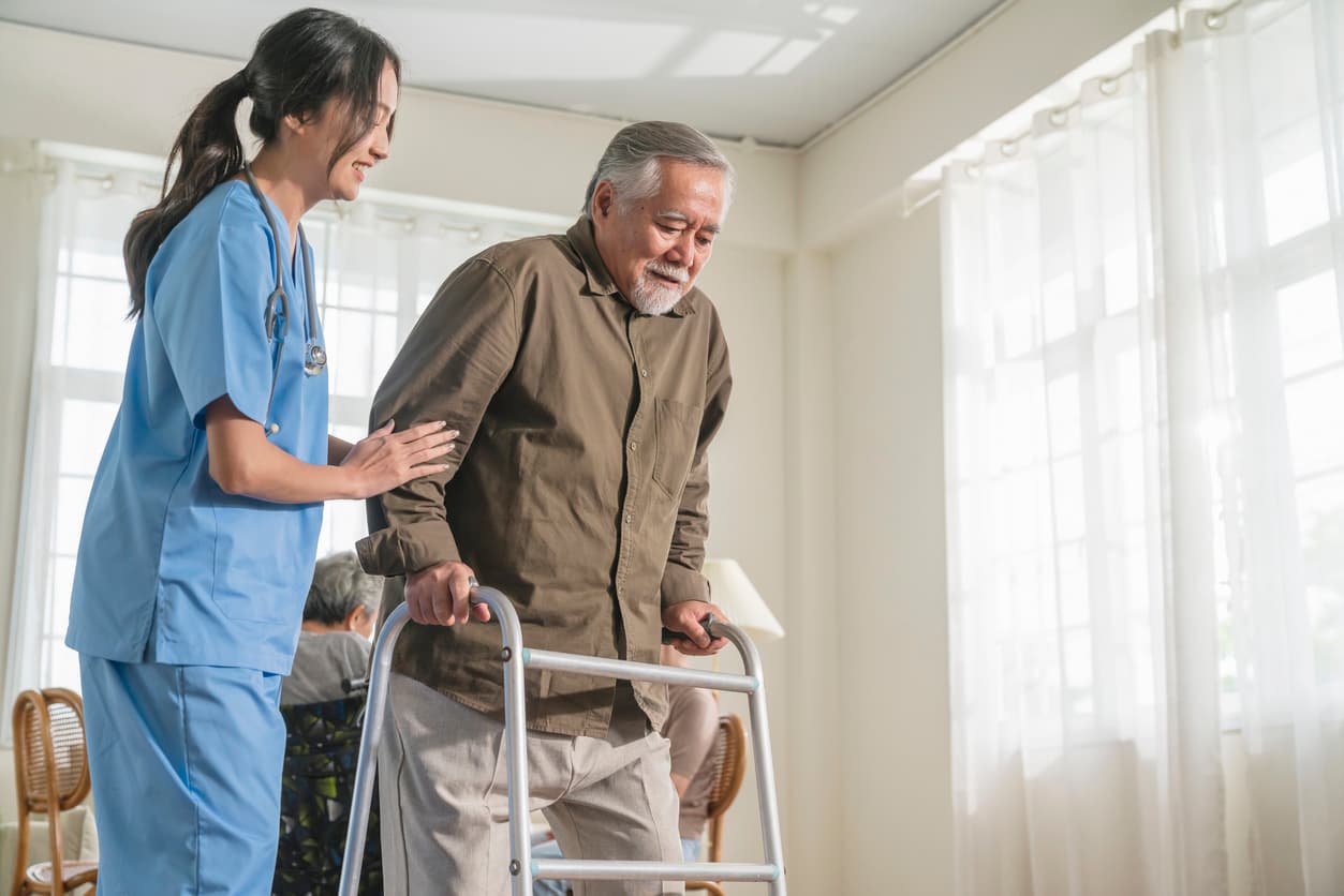 Caregiver assisting a senior man using a walker during rehabilitation