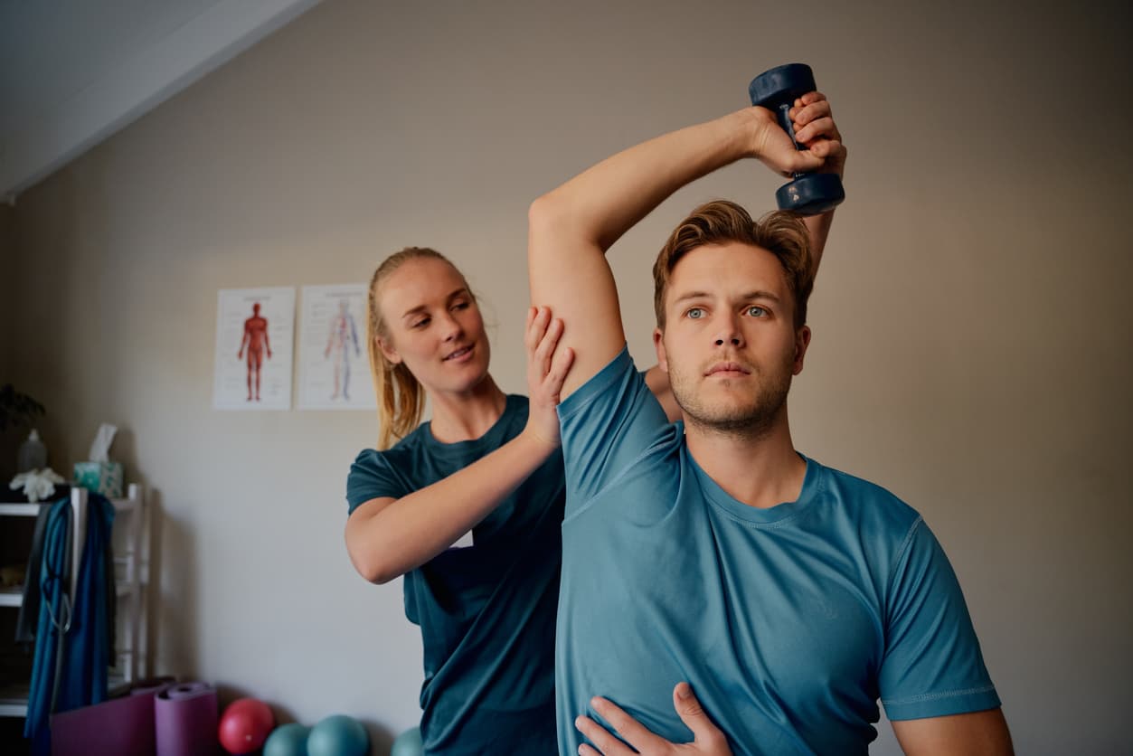 Physiotherapist assisting patient with shoulder strengthening exercise