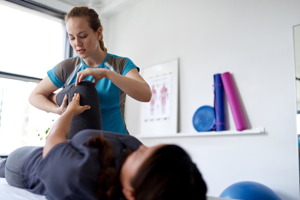 Physical therapist assessing patient knee during rehabilitation session