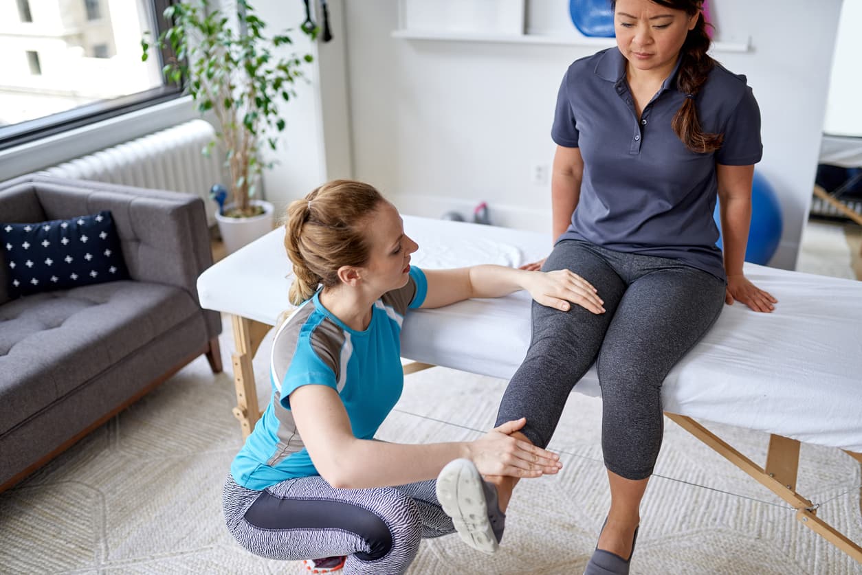 Physical therapist examining patient’s leg during rehabilitation session