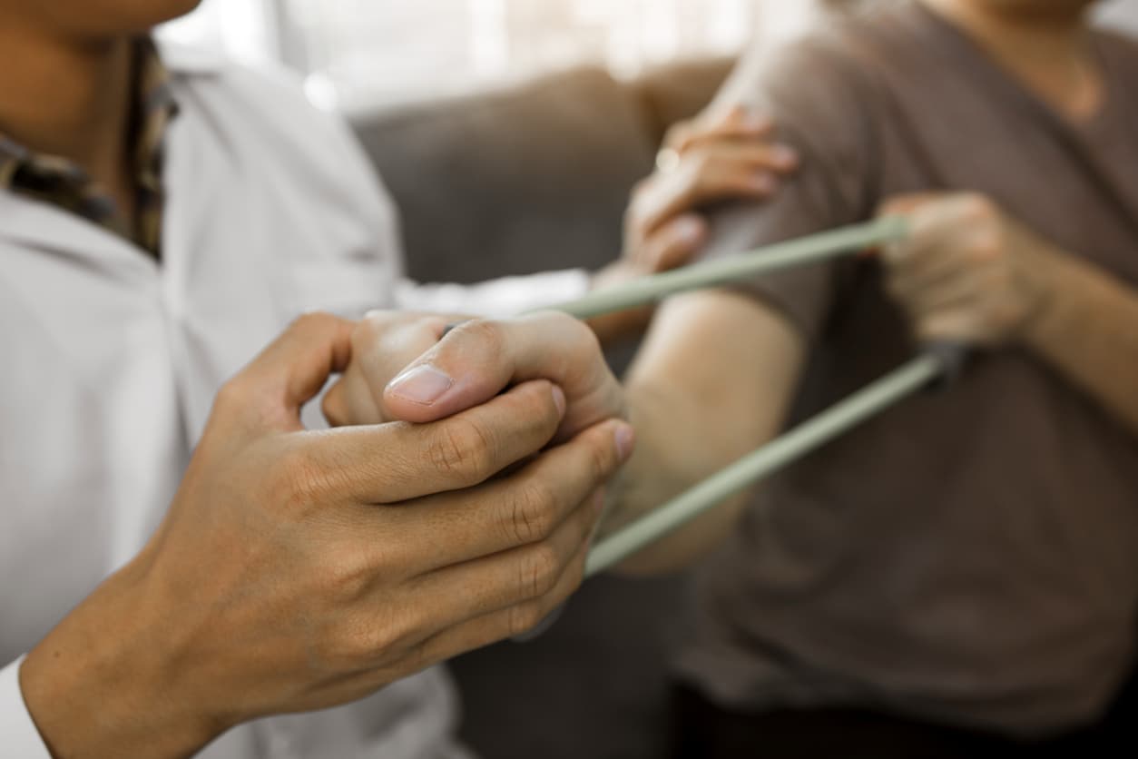 Therapist guiding patient through resistance band arm rehabilitation exercise