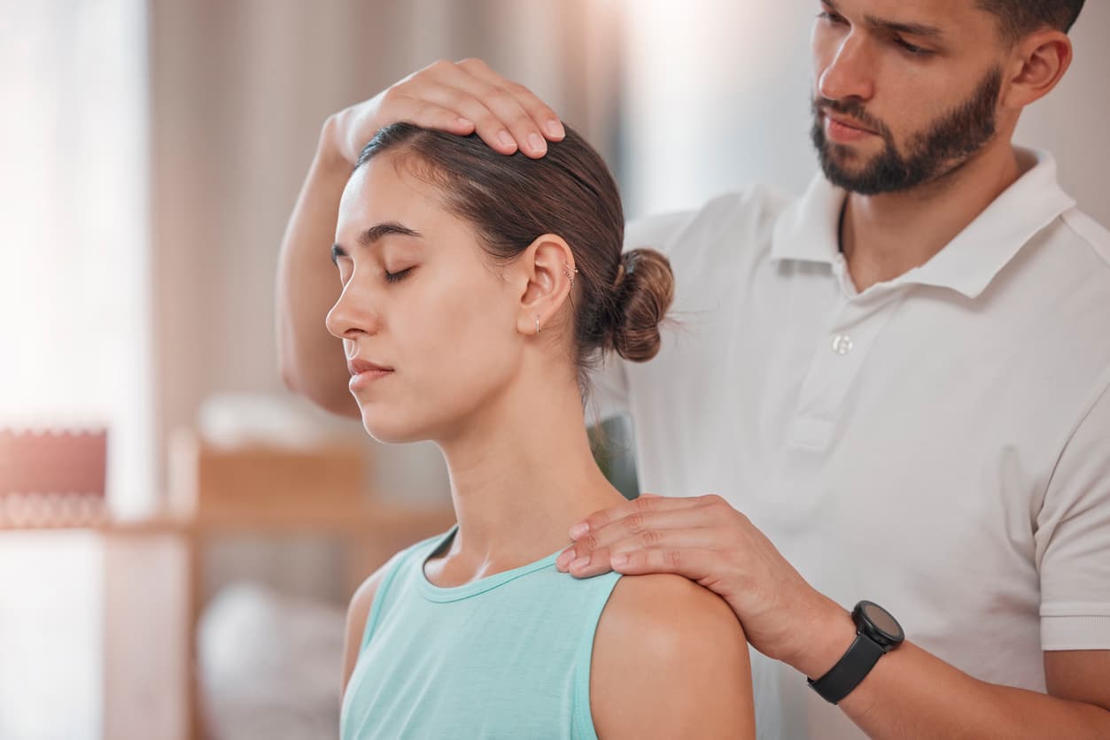 Therapist performing a neck and posture assessment on a young woman